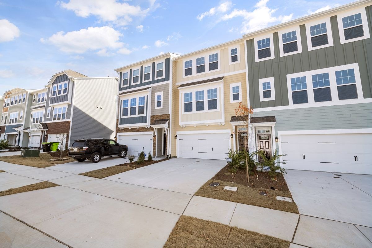 Row of colourful three-storey townhouses with garages under a bright blue sky